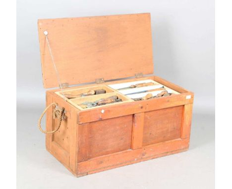 A mid-20th century toolbox, containing a selection of carpentry tools, including chisels, saws and planes.