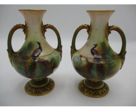 A pair of small early 20th century Royal Worcester vases of bulbous form with twin handles, on a splayed foot decorated with 