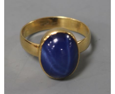 A cabochon star sapphire ring, yellow metal rubover setting and shank, size O.