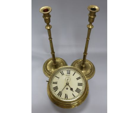 A brass bulkhead clock by Sewell, Maker to the Admiralty, Liverpool and a pair of tall brass slender candlesticks each with k