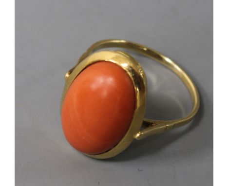 A yellow metal and oval cabochon coral ring, size R.