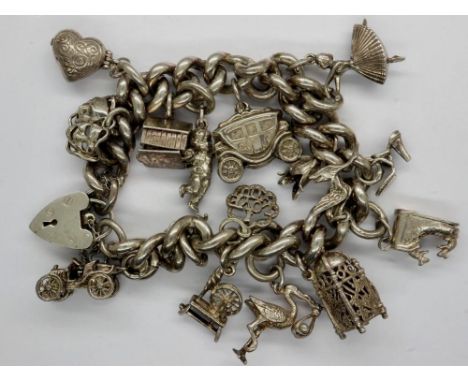 Hallmarked silver charm bracelet with sixteen charms, padlock clasp and safety chain, L: 18 cm, 106g. UK P&amp;P Group 0 (£6+