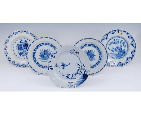 An English blue and white Delftware plate, 18th century, decorated with flowers beside a fence, dia.23cm; together with four 