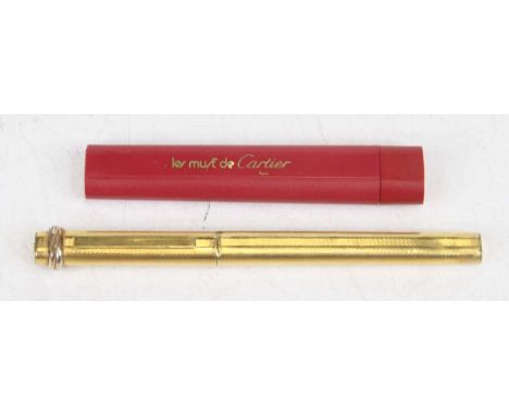 A Must de Cartier gold plated cased ballpoint pen, of rounded rectangular form, having engine turned decoration, numbered 004