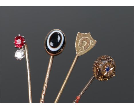 Stick pins, to include a garnet and diamond example, a banded agate example, a sapphire example and a shield example, (4)