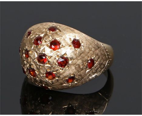 14 carat gold garnet set ring, the raised dome head set with sixteen garnets, ring size J, 4.7 grams