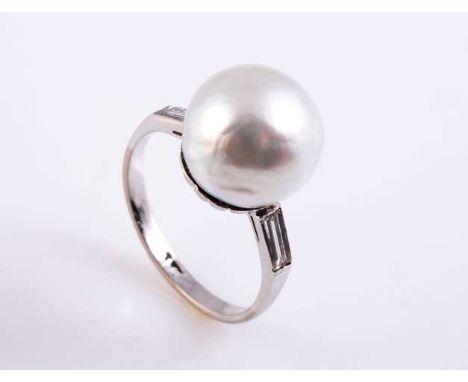 A CULTURED PEARL AND DIAMOND RING
The large cultured pearl set in a moulded detail mount between shoulders each simply set wi