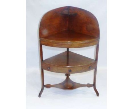 A GEORGE III MAHOGANY CORNER WASHSTAND
Bow-fronted, fitted with a drawer flanked by a pair of dummy drawers, raised on splaye