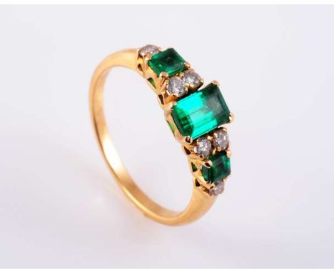 AN EMERALD AND DIAMOND RING
The rectangular cut emerald four claw set between four brilliant cut four claw set diamond highli