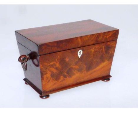 A 19TH CENTURY MAHOGANY TEA CADDY
Of tapering rectangular form with ring handles and flattened bun feet, the interior with tw