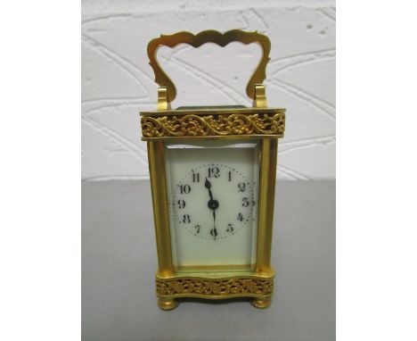 An early 20th century French brass cased carriage clock, five windows with pierced, blind floral decoration, white enamelled 