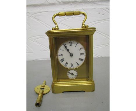 An early 20th century French lacquered brass cased alarm carriage clock, striking on a bell, white enamelled dial with Roman 