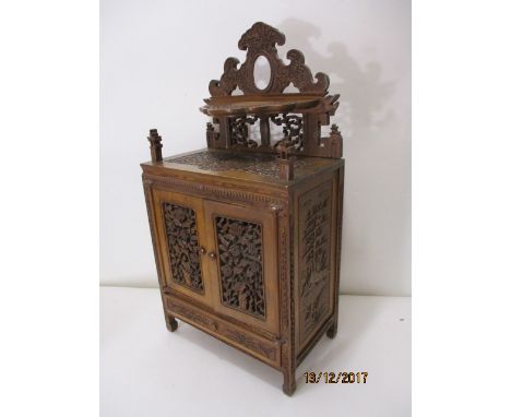 A late 19th century oriental profusely carved, hardwood table cabinet with floral decoration having a detachable back with a 