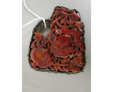 An early 20th century Chinese carved amber plaque brooch depicting fruit amongst leafy branches, set in a silver filigree and