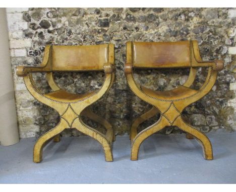 A pair of early 20th century light tan, hide and brass stud upholstered Savonarola design chairs, having a rectangular back, 