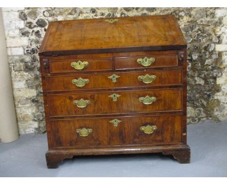 A mid 18th century cross and feather banded walnut bureau, the fall front enclosing a fitted interior over two short and thre