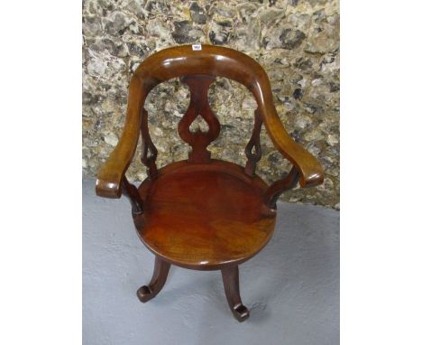 A late Victorian mahogany rotating desk chair having an arched back, curved arms and moulded seat, raised on curved legs and 