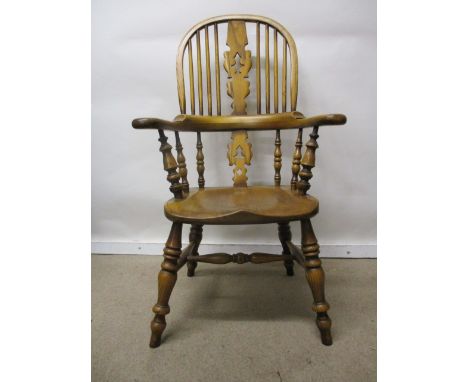 A Stewart Linford child's Windsor oak chair having a hoop and spindle back with a pierced splat, level arms and moulded seat,