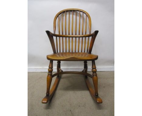 A Stewart Linford child's ash and elm Windsor rocking chair having a hoop and spindle back, level arms and moulded seat, rais