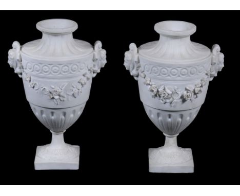  A pair of French bisque porcelain urns,   19th century , with mask handles suspended with garlands of flowers, on square bas