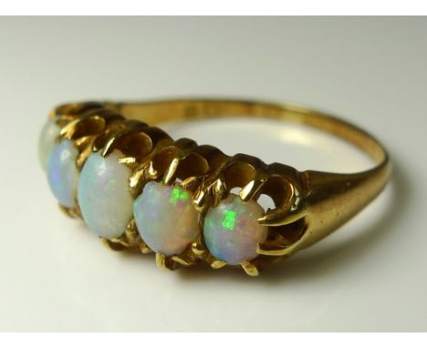 An Edwardian opal ring, the five graduated oval stones claw set in a pierced yellow metal band, size Q, 3.8g.