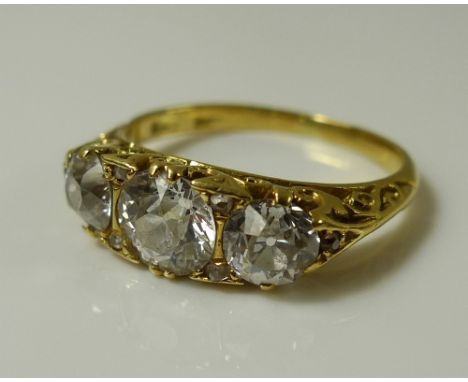 An 18ct gold and diamond three stone ring, the central diamond of approximately 0.75ct and flanked by a diamond of approximat