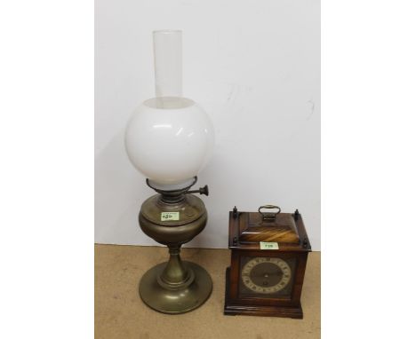 A mantel clock with brass details plus an oil lamp with shades
