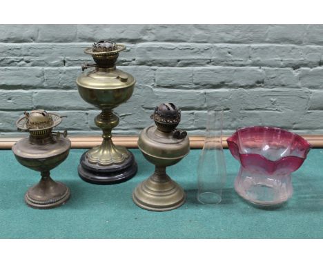 Three brass oil lamp bases plus a cranberry glass shade