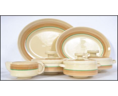 An Art Deco part dinner service by Clarice Cliff for Wilkinsons Ltd to include lidded tureens, ladle, graduating platters. Pl