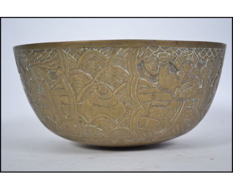 An early 20th century Chinese brass bowl with heavy detailed chasing depicting fighting / duelling between oriental warriors.