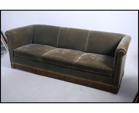 A large early 20th century knoll style sofa settee being upholstered in a green velour fabric having deep squared arms an bac