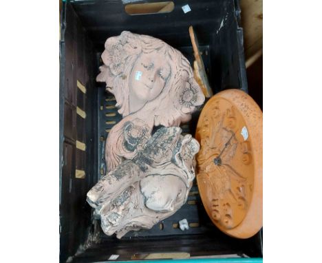 A crate containing a pair of plaster garden wall decorations, a terracotta thermometer of circular form and a studio pottery 