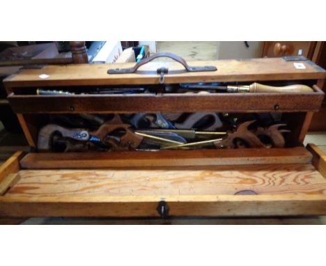 A carpenter's toolbox containing a collection of vintage saws and other tools