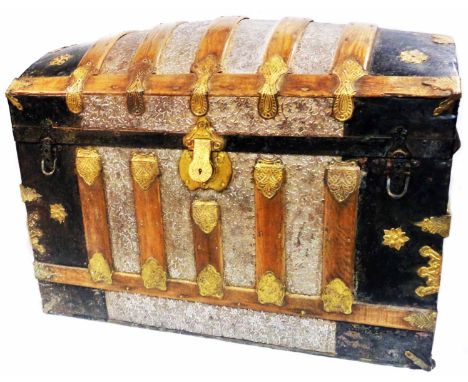 An 81cm late 19th Century dome-top travelling trunk with decorative pressed metal cladding, wood and brass bound, the paper l