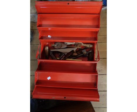 A red cantilever toolbox containing tools including spoke shaves, wood plane, etc.