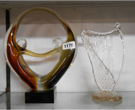 A large coloured glass free form sculpture depicting figures holding hands - sold with a glass harp ornament