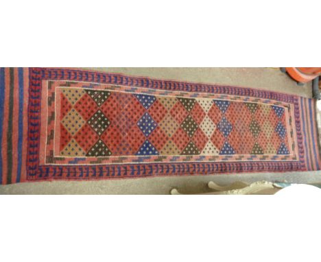 A vintage North African handmade wool runner with central geometric design within a stylised foliate border, on red ground - 