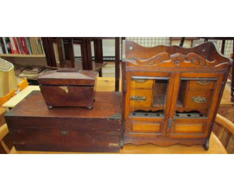 An oak smokers cabinet, with a carved cresting above a pair of glazed doors enclosing drawers together with a mahogany laptop