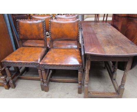 An oak gate leg dining table with an oval top and drop flaps together with a set of four leather and oak dining chairs