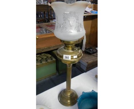 A brass oil lamp with shade and chimney.