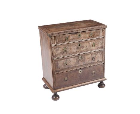 An early 18th Century walnut bachelor’s chest, the turnover top with re-entrant corners and feather banding, with turnover to