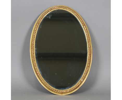A late George III giltwood and gesso oval wall mirror with a beaded frame, 61cm x 41cm (later glass). Provenance: the propert