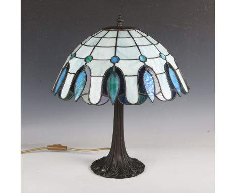 A modern Tiffany style table lamp, the conical blue glass shade with stylized foliate rim above a similarly cast patinated me