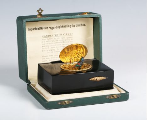An early 20th century Continental black composite cased singing bird musical box, the top with a hinged gilt metal lid enclos
