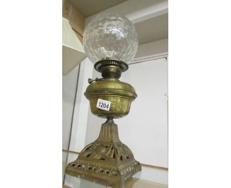 A Victorian oil lamp with brass font on cast iron base with burner and shade but missing chimney.
