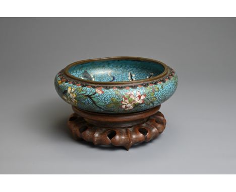 A CHINESE CLOISONNE ENAMEL BOWL WITH WOODEN STAND, 19/20TH CENTURY. With rounded sides decorated with various floral blossoms