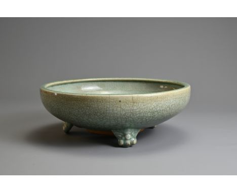 A LARGE CHINESE LONGQUAN CELADON TRIPOD CENSER, MING DYNASTY. Heavily potted on three lion mask feet covered in a green glaze