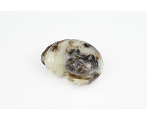 A PALE AND DARK GREY JADE PENDANT CARVING OF A CAT, QING DYNASTY. The cat recumbent with its legs tucked under its body in a 