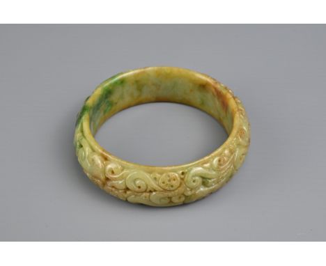 A CARVED CHINESE JADE BANGLE. Carved in relief with bat and lingzhi spray. The jade with yellow, brown and green tones. Outer