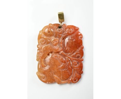 A CHINESE CARVED ORANGE JADE PENDANT. Carved in relief with monkey on peach group with yellow metal mount. 5cm x 4cm. Weight 
